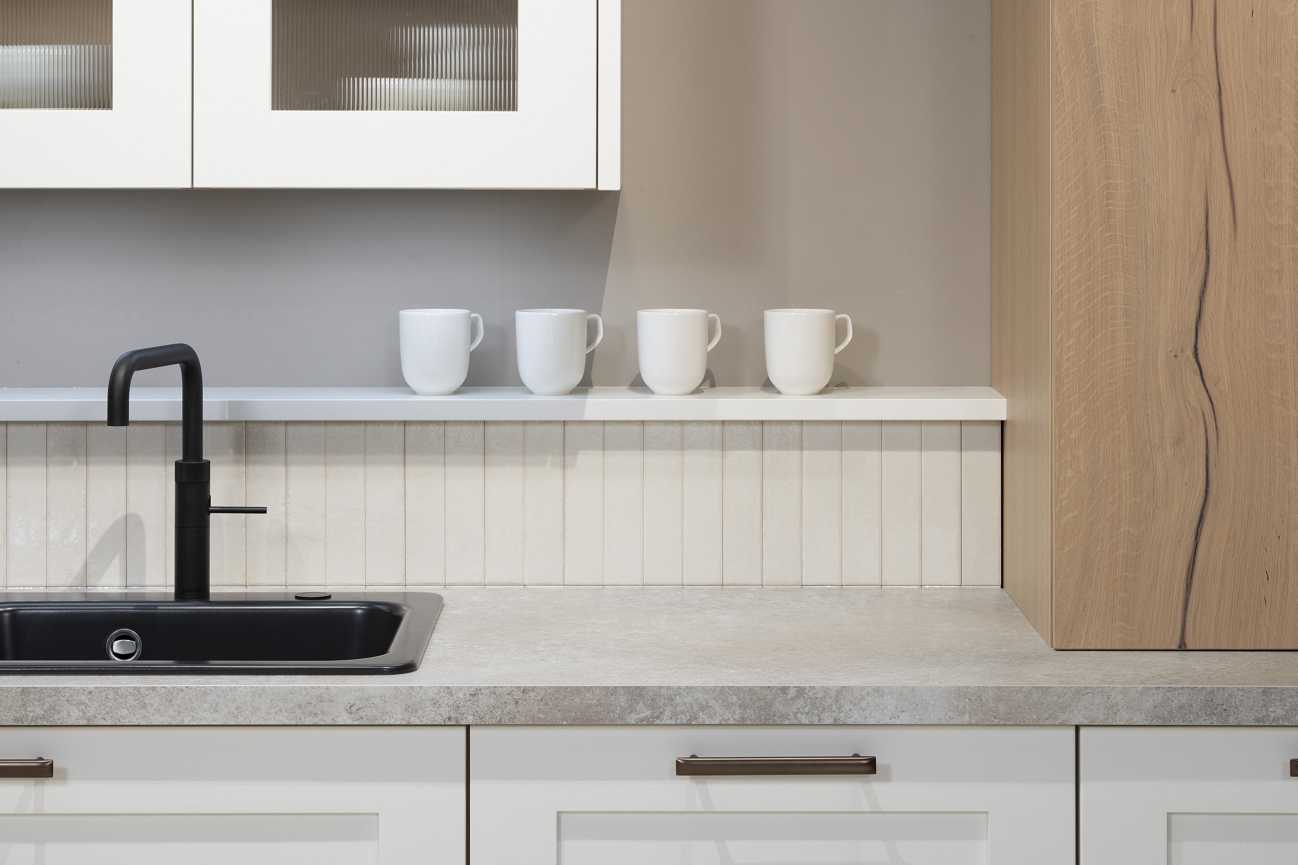 APL: 15 Kalkstein Repro 25 mm Front: AV 6055 Weiß Echtholz lackiert,  Front 2: AV 6082 Wildeiche-natur Korpus: 2085 Designkorpus Feineiche-natur Griff: 515 Metall Bronze-dunkel Geräte: Bosch  Armatur: Quooker Spüle: Systemceram   Features: Landhausküche modern, Echtholz RAL und NCS lackierbar, Riffelglasvitrine, Beleuchtung, schwebender Block, Echtholzfurnier lackiert kombiniert mit Echtholzfurnier, Fliesen, Korpus Echtholz Feineiche Natur, Griffe in Bronze. 