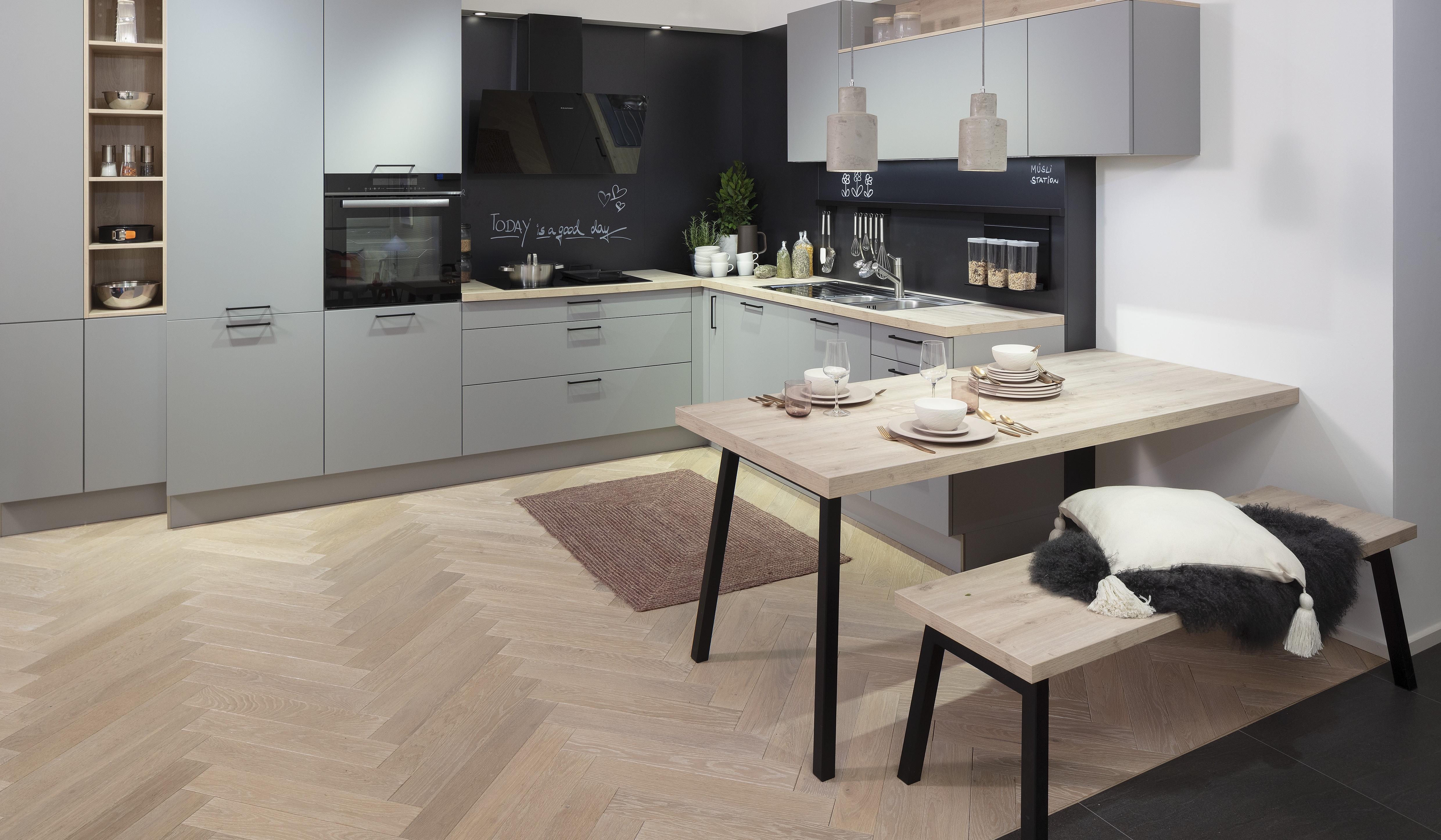 Moderne Küche mit grauen Schränken, Holztisch und gepolsterter Bank